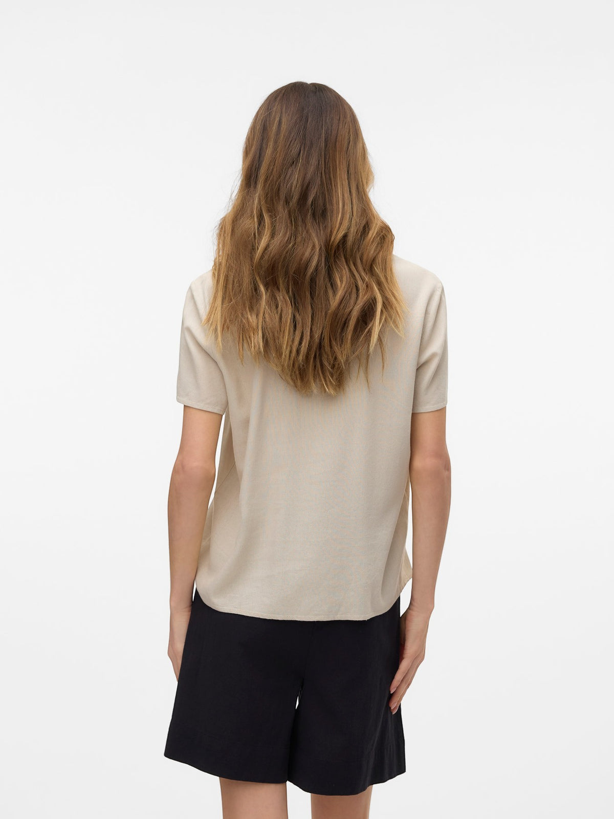 Antique Rose Boutique beige linen mix short sleeve blouse viewed from the back on a model with long wavy hair.