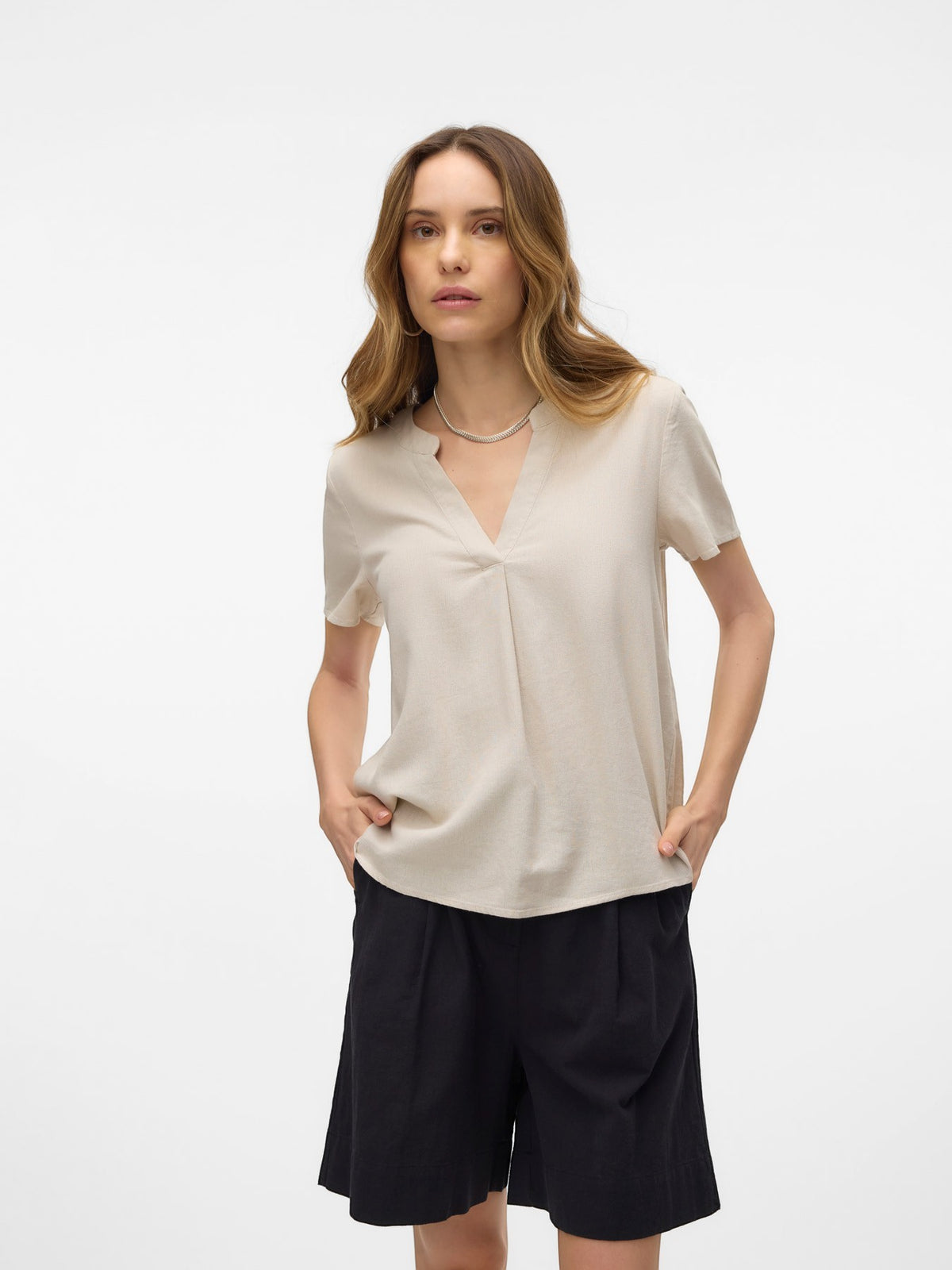 Antique Rose Boutique beige linen mix V-neck short sleeve blouse worn by a model with black trousers