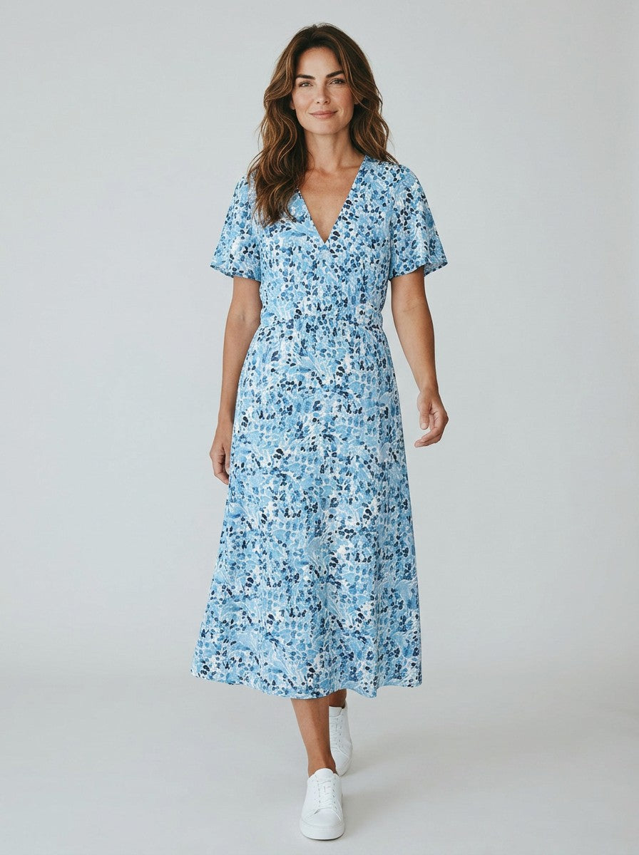 Antique Rose Boutique blue floral print maxi dress with V-neck and flutter sleeves worn by a woman with white sneakers