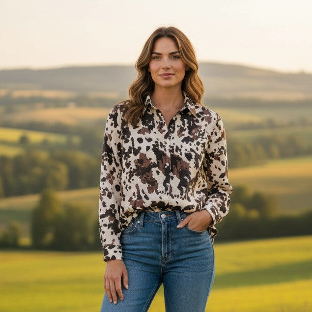 Antique Rose Boutique cow print viscose shirt in chocolate and cream worn with blue jeans in a scenic field