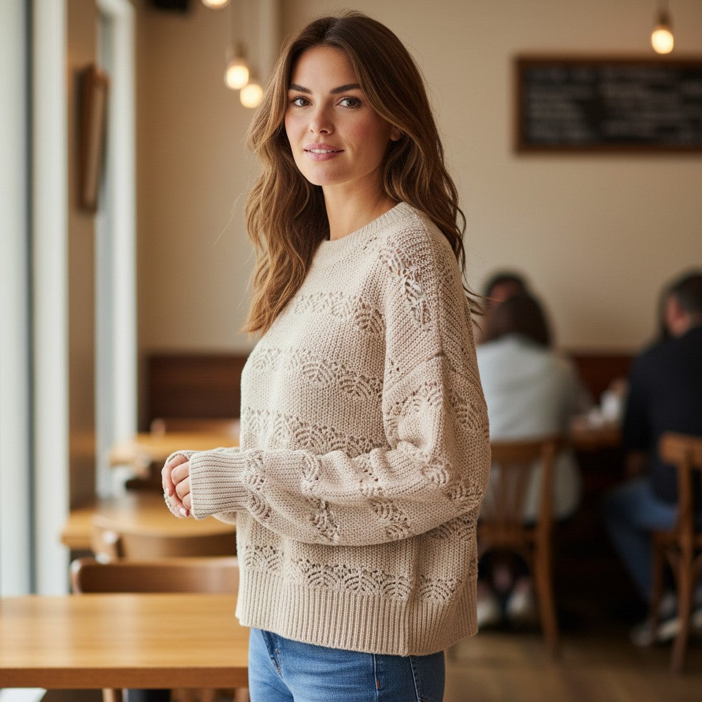 Antique Rose Boutique cream fine knit round neck jumper with long sleeves and ribbed cuffs worn by a woman in a cafe