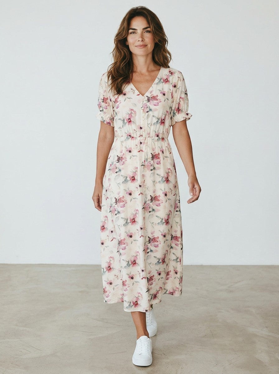 Antique Rose Boutique floral midi dress with V-neck, puff sleeves, and elastic waist worn by a woman with white sneakers.