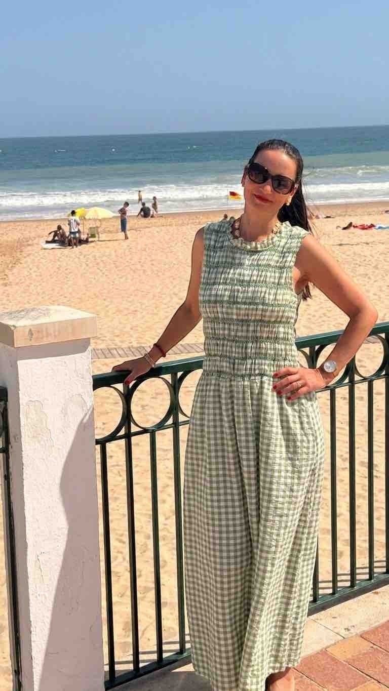 Antique Rose Boutique sleeveless green gingham maxi dress with a smocked bodice worn by a woman at the beach.