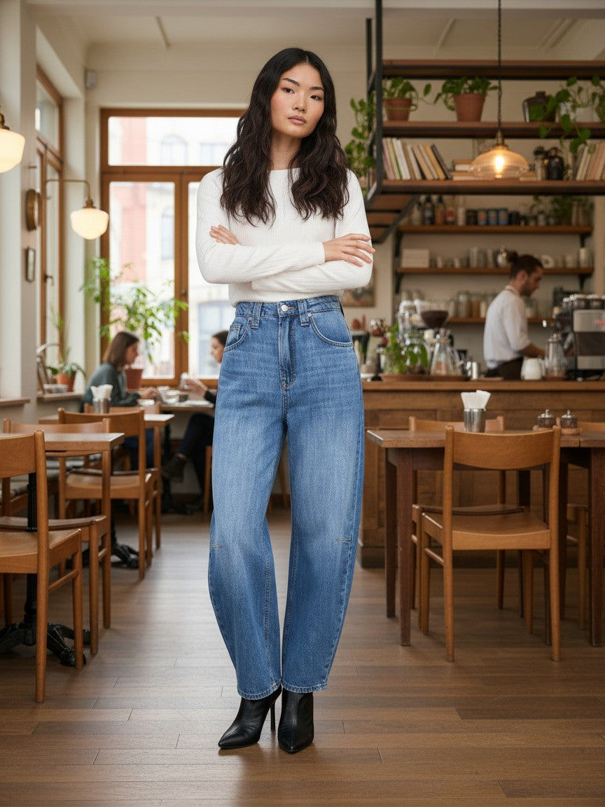 Antique Rose Boutique Frankie high-waisted barrel jeans in medium blue denim worn by a model in a cafe.
