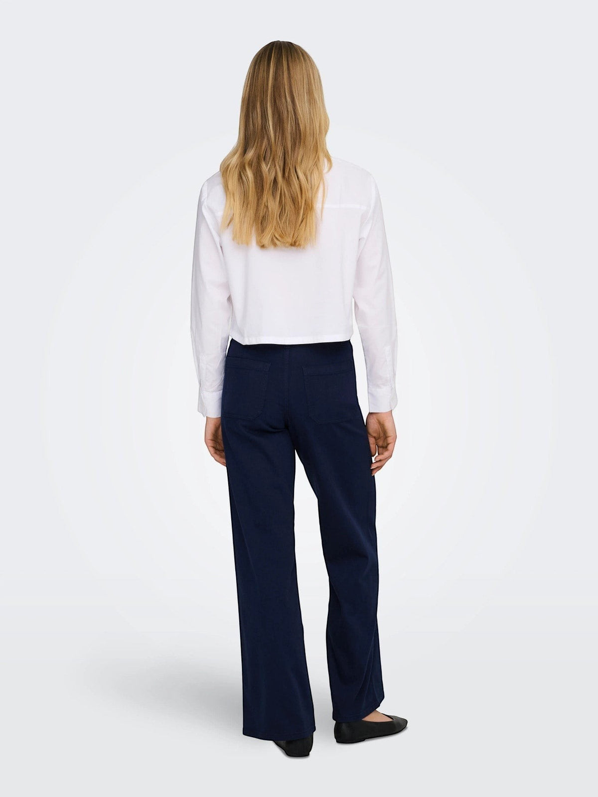 Antique Rose Boutique navy blue wide leg high waist denim trousers worn by a woman with a white shirt, back view