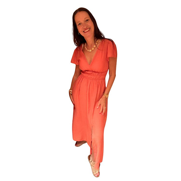 Antique Rose Boutique model wearing a langoustino orange V-neck midi dress with short sleeves and a gathered waist.