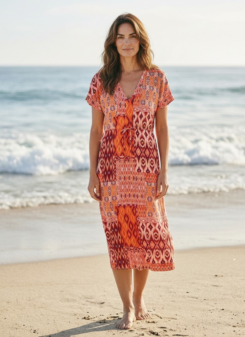 Antique Rose Boutique Vero Moda orange and red patchwork kaftan dress with V-neck and tie waist on a sandy beach