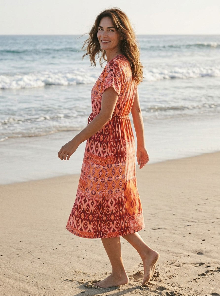 Antique Rose Boutique Vero Moda kaftan dress in orange and red patchwork print with V-neck and tie waist on a beach