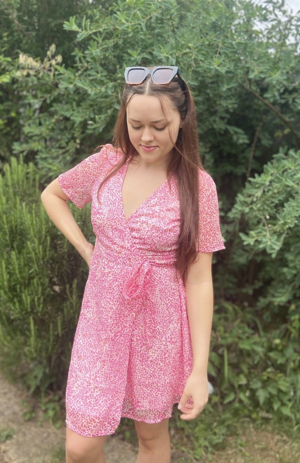 Antique Rose Boutique pink animal print wrap mini dress with short sleeves and V-neckline worn by a woman outdoors