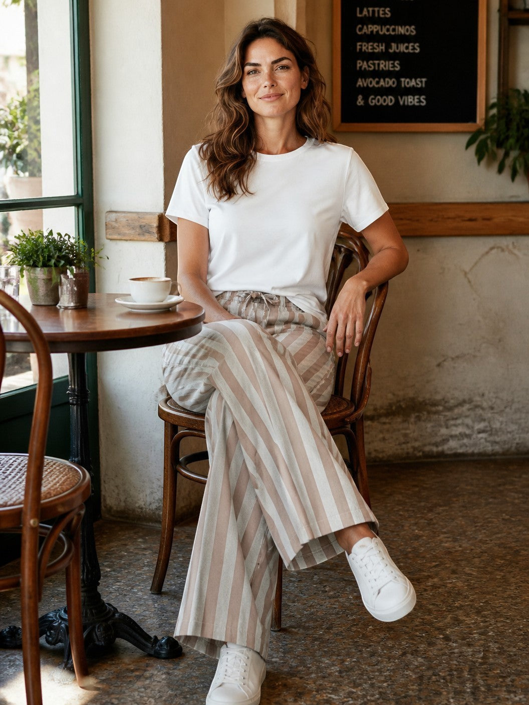 Antique Rose Boutique striped linen wide-leg trousers with drawstring waist worn by a woman in a cafe setting.