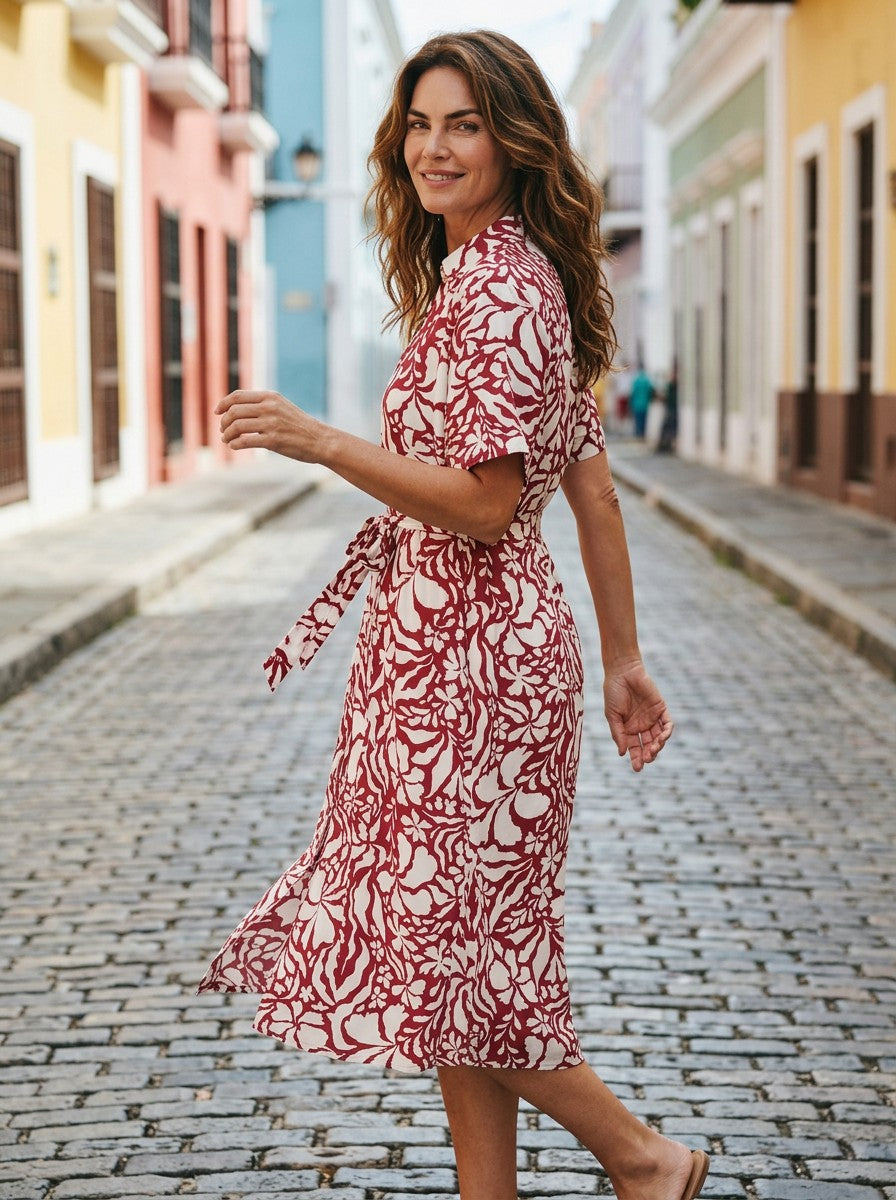 Antique Rose Boutique Yasmin midi dress in dark red with white floral print, V-neck, and waist belt on a city street.